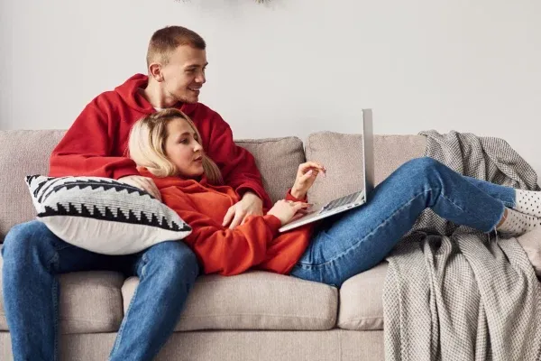 a couple in red sweatershirts looking at laptop
